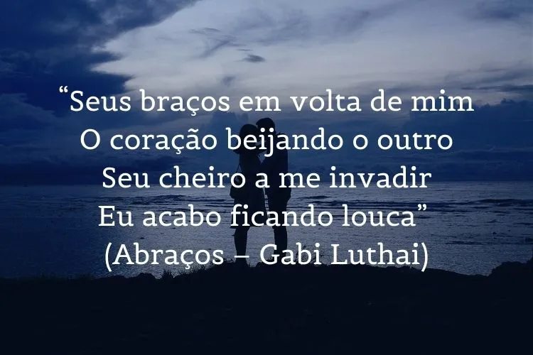 Foto de casal abraçado no pôr do sol e frase:  “Seus braços em volta de mim / O coração beijando o outro / Seu cheiro a me invadir / Eu acabo ficando louca” (Abraços – Gabi Luthai)