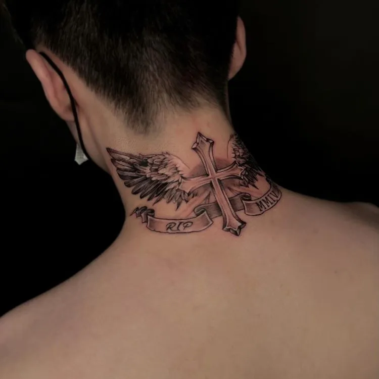 A imagem mostra uma pessoa de costas com cabelo curto. Ela tem uma tatuagem no pescoço de uma cruz com asas abertas, detalhada em preto e cinza. Abaixo da cruz, há uma faixa com as inscrições "RIP" e "MMIV". A tatuagem cobre a parte de trás do pescoço até os ombros.




