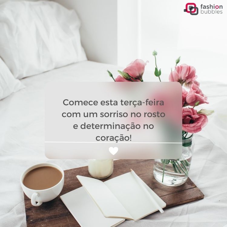 Foto de cama desarrumada com lençóis brancos e bandeja com xícara de café, livro e flores rosas, além de frase dentro de retângulo desfocado " Comece esta terça-feira com um sorriso no rosto e determinação no coração!"