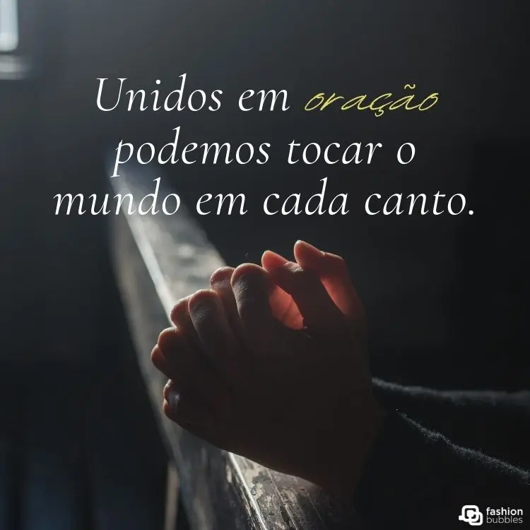 Mãos entrelaçadas em posição de oração, apoiadas em um banco de madeira, com luz suave iluminando o ambiente. A frase "Unidos em oração podemos tocar o mundo em cada canto" aparece destacada sobre fundo escuro, transmitindo espiritualidade.