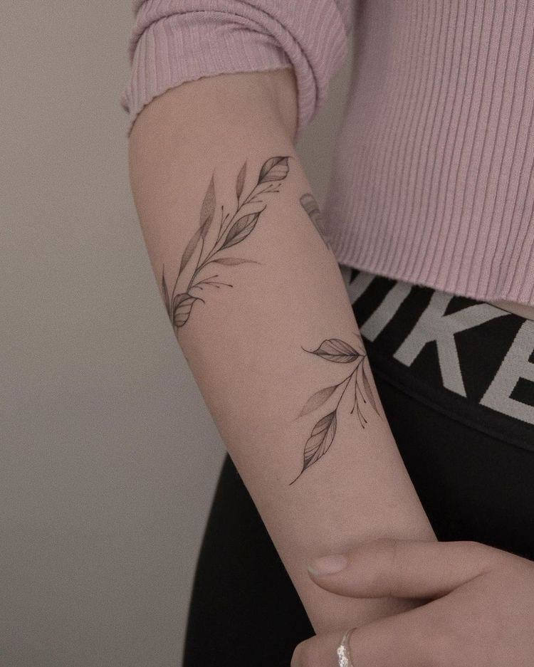 Tatuagem de ramo de folhas formando bracelete 
