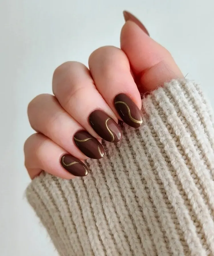 Foto de unhas pintadas com esmalte marrom, uma das tendências de unhas para 2026