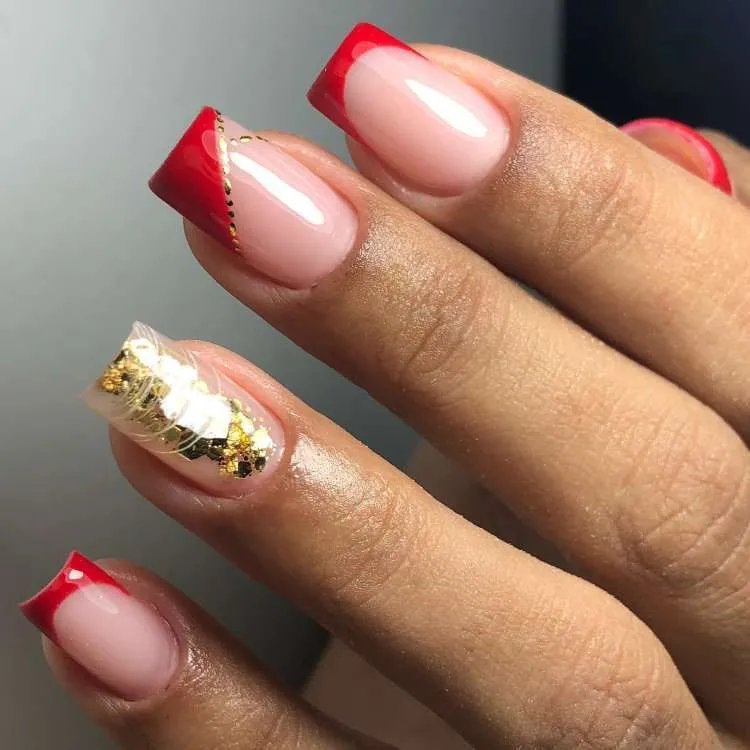 Mão de pele morena com unhas quadradas com nail art de francesinha, outra de brilho encapsulado e teia e outra de vermelho na diagonal