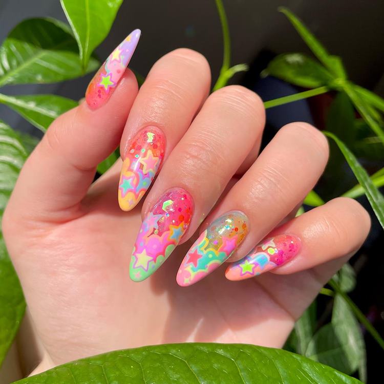 Unha para Carnaval colorida com glitter e adesivo de estrelas con nuvens cores pastéis