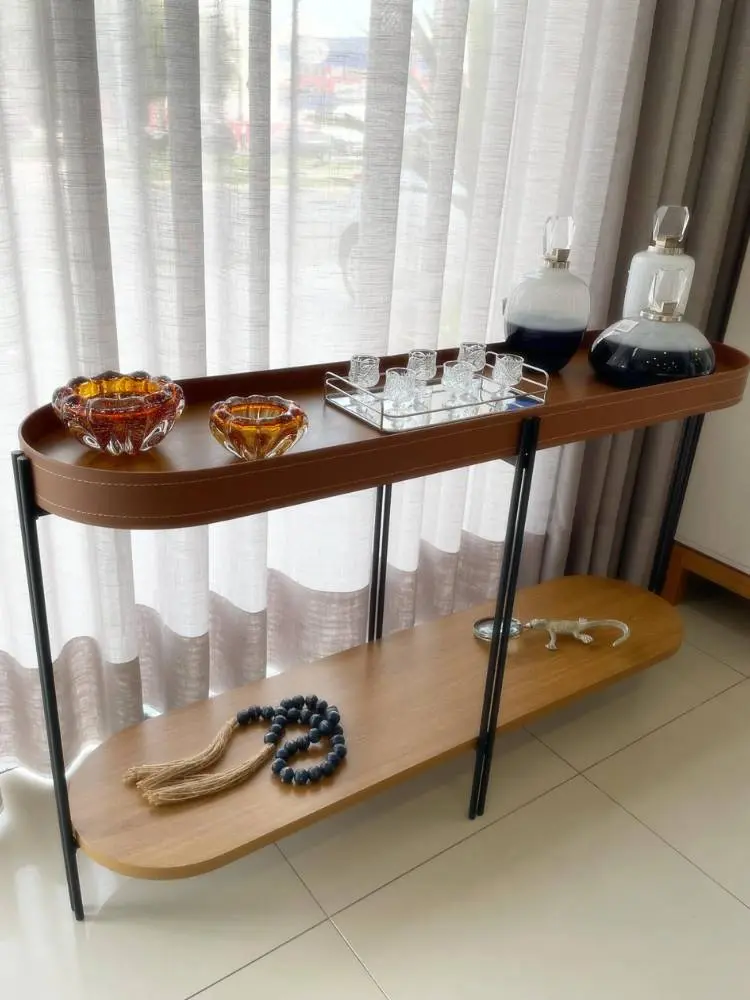 Aparador com estrutura em aço, tampo arredondado, acabamento em couro ecológico e costuras aparente, com itens decorativos como correntes, copos, baleiros e potes