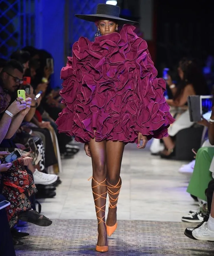 Foto de modelo na passarela usando vestido roxo volumoso e scarpin laranja
