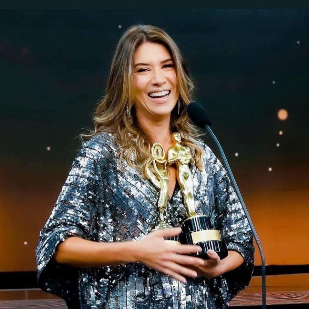 Rebeca Abravanel com troféu em um palco com microfone