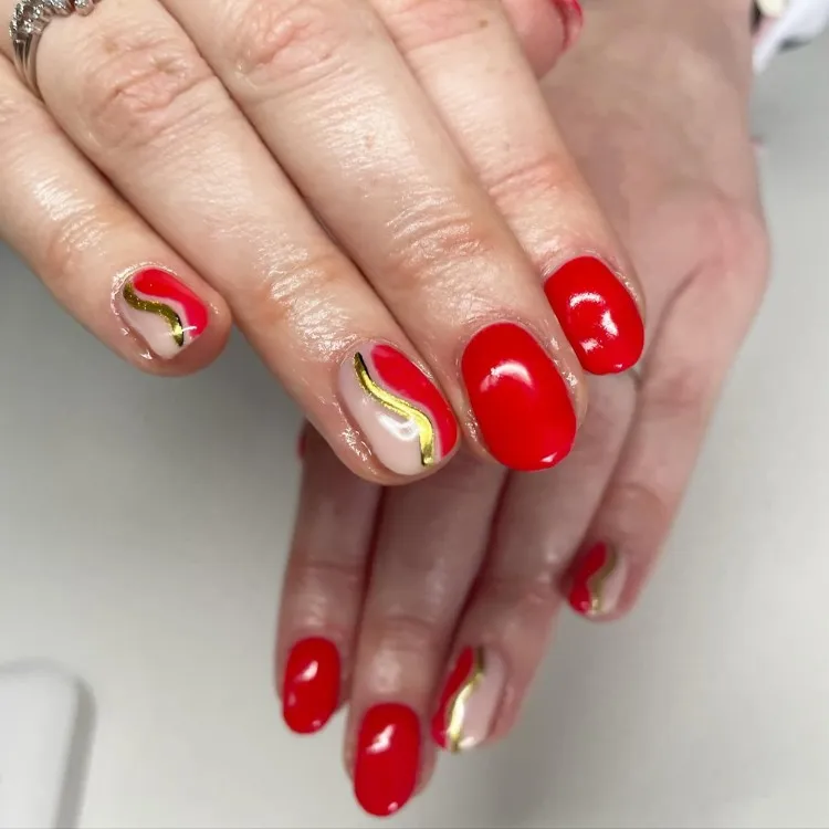 Unhas redondas vermelhas com traço dourado 