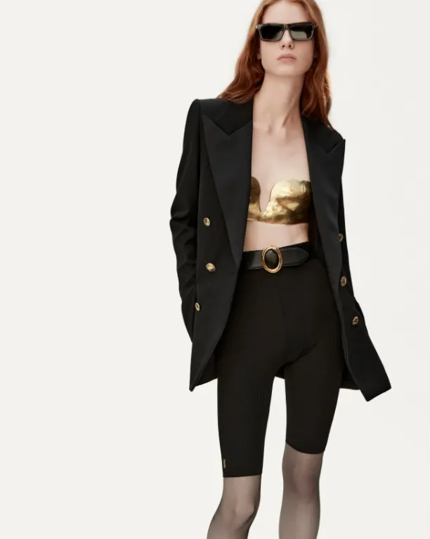 Blazer, bermuda ciclista, meia-calça, cinto e top dourado.