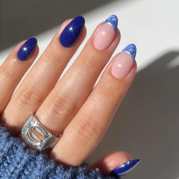 Mão de pele clara com unhas azul marinho e duas com francesinha azul marmorizada 
