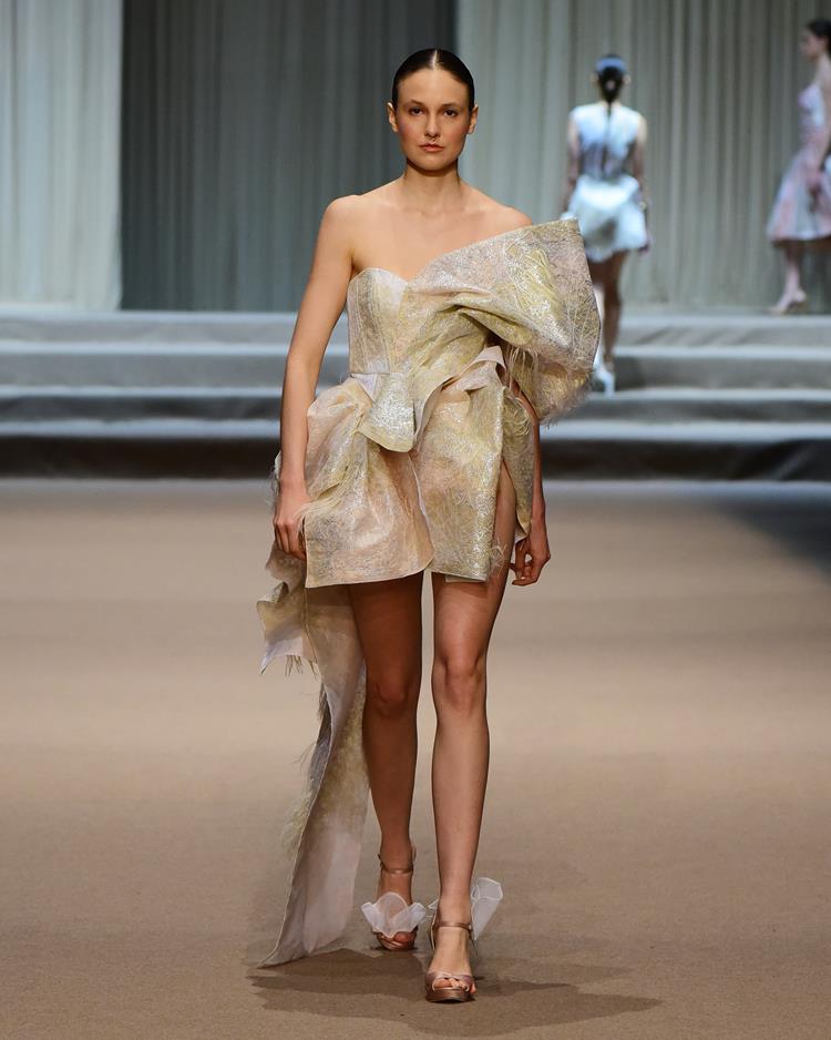 modelo no desfile Melk Z-Da com vestido curto branco e dourado