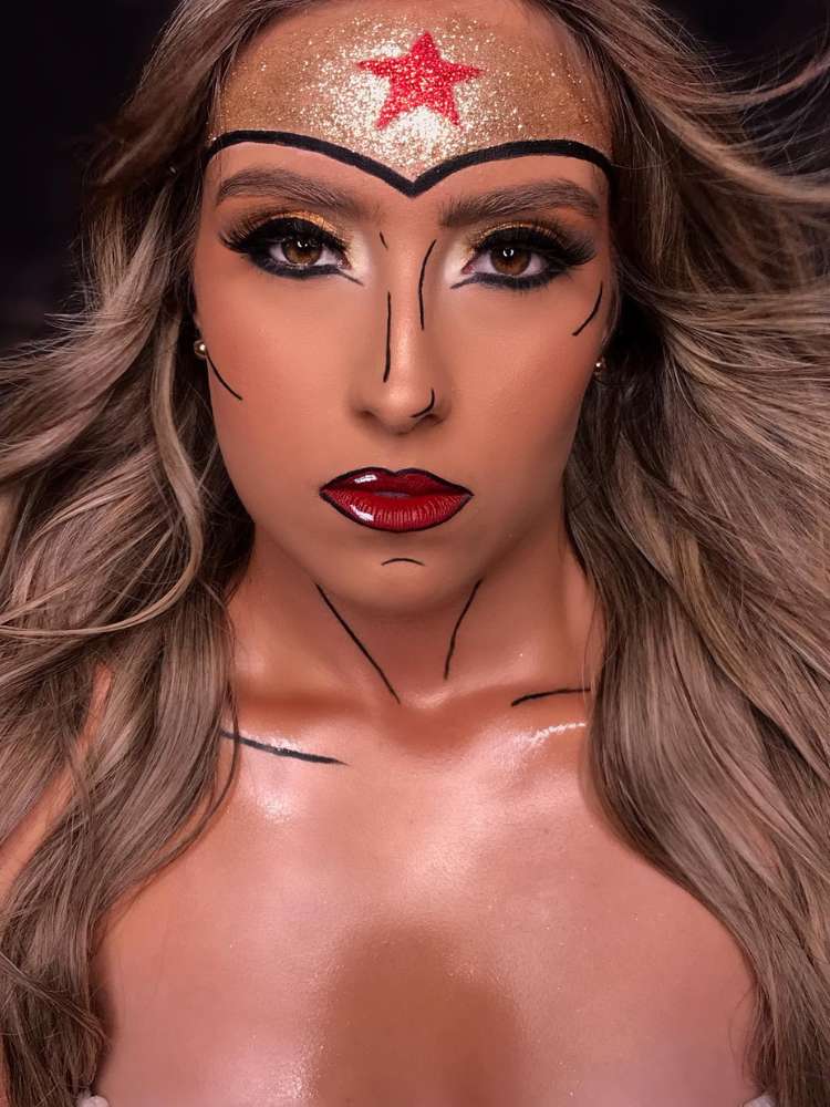 Mulher de pele clara e cabelo loiro com maquiagem artística da Mulher Maravilha.