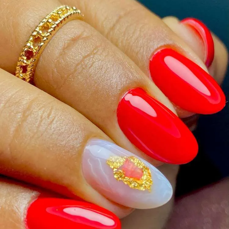 Nail art com vermelho, arte dourada na filha única com técnica mármore