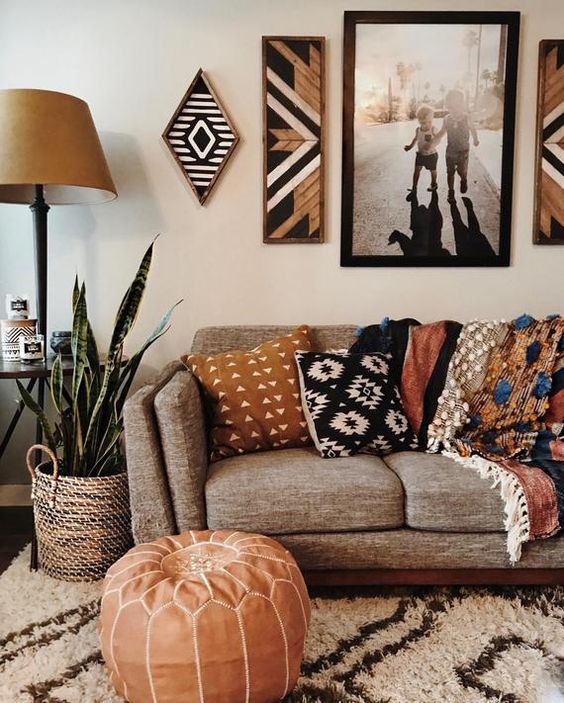 Decoração de outono na sala, com quadros, sofá com almofadas, espada-de-são-jorge, puff laranja 